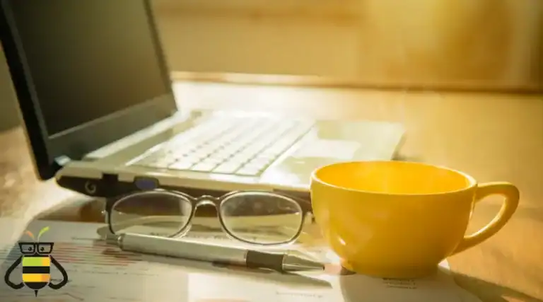 A laptop with glasses and a coffee mug sitting next to it