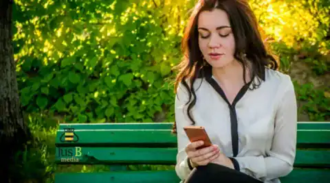 girl sitting on a bench looking at her phone