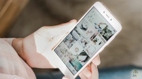Phone in hand with screen showing Instagram grid