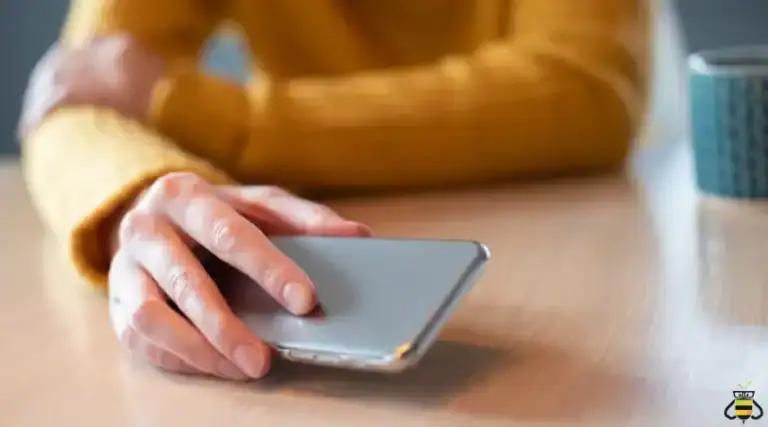 Hand holding a cell phone at a table