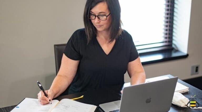 person sitting at writing in planner with laptop open