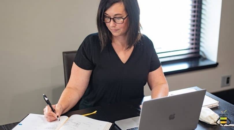person sitting at writing in planner with laptop open