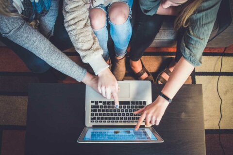 people pointing at the screen on a laptop