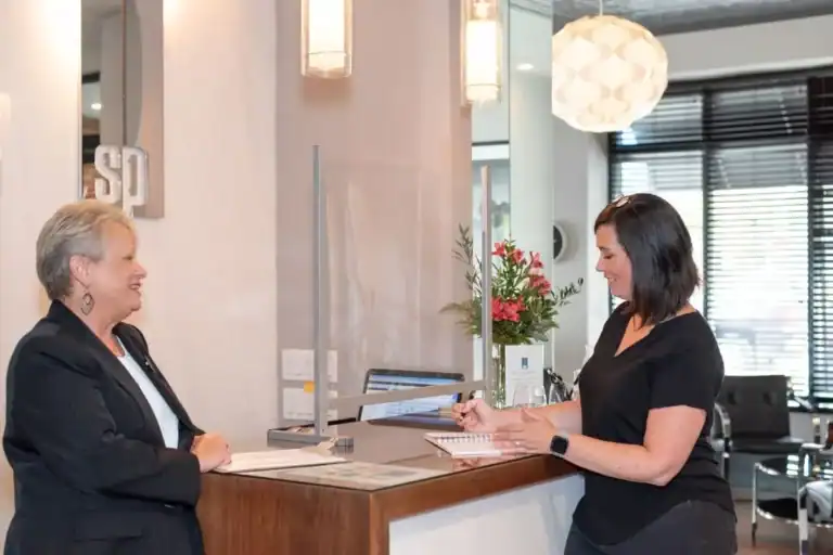 two women standing at a front desk talking to one another