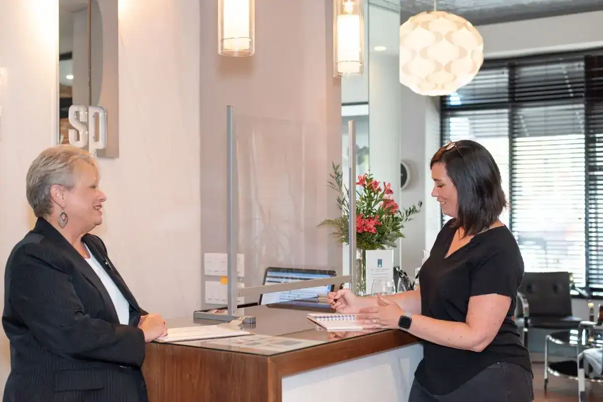 two women standing at a front desk talking to one another