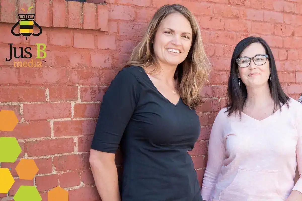 two females leaning up against a brick wall