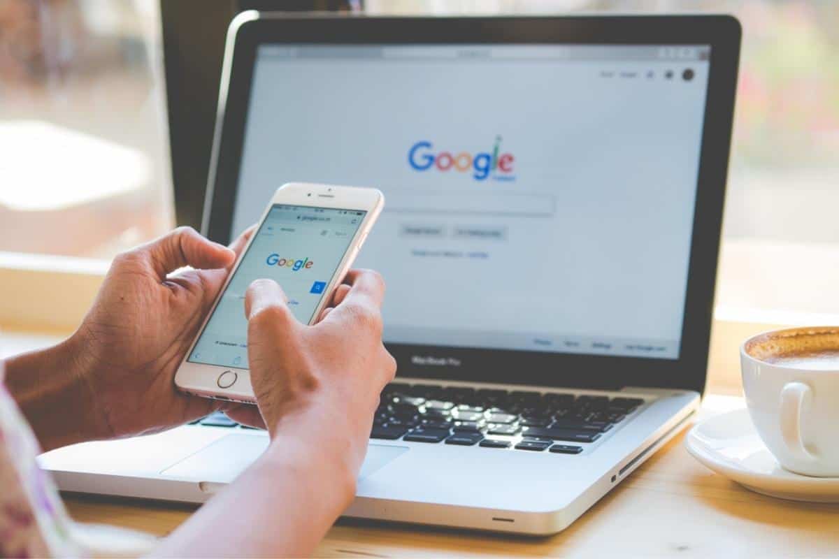 Person holding a phone sitting in front of a laptop