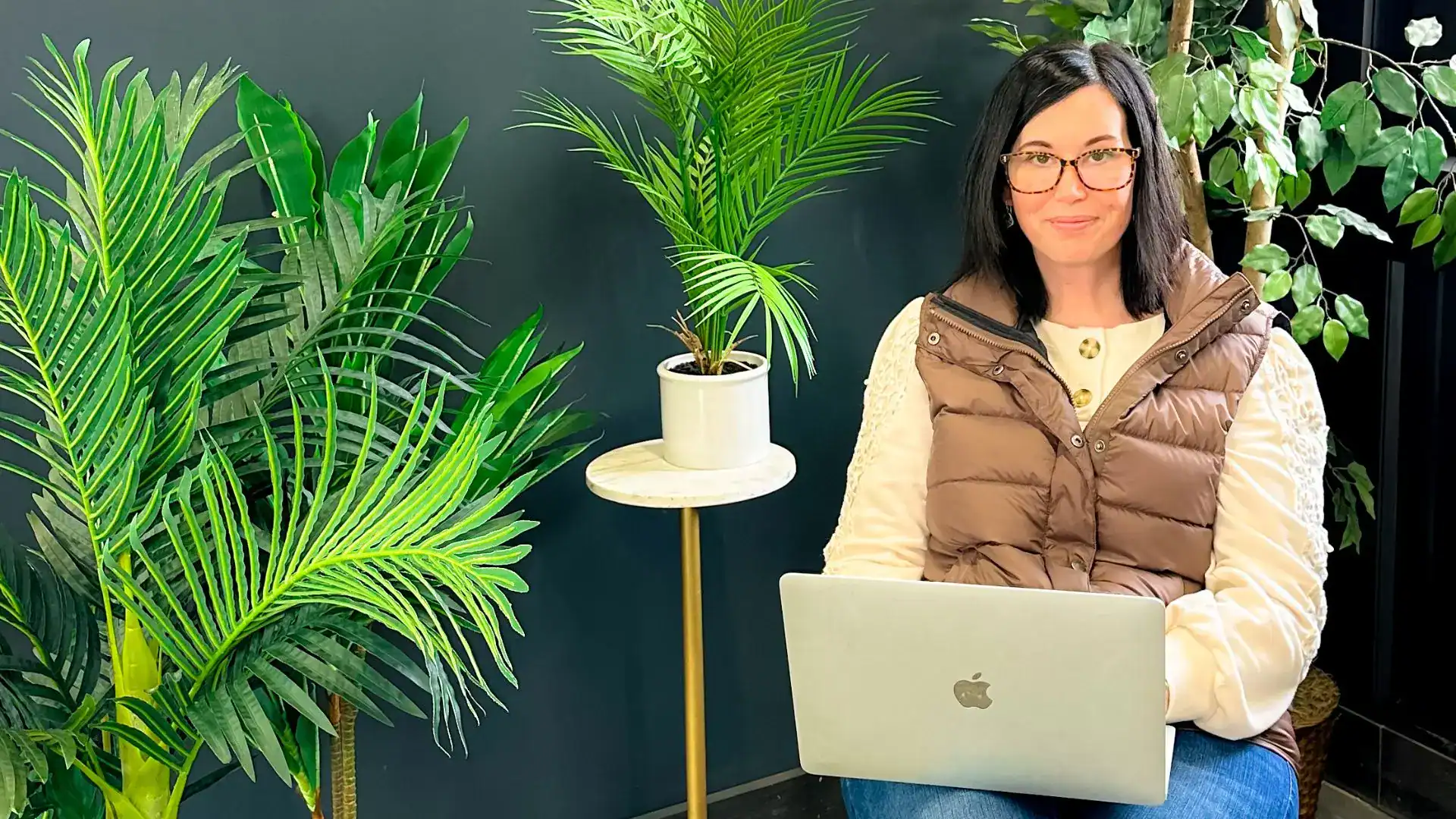 Woman sitting with a laptop in her lap looking up the camera thinking about messaging clarity.